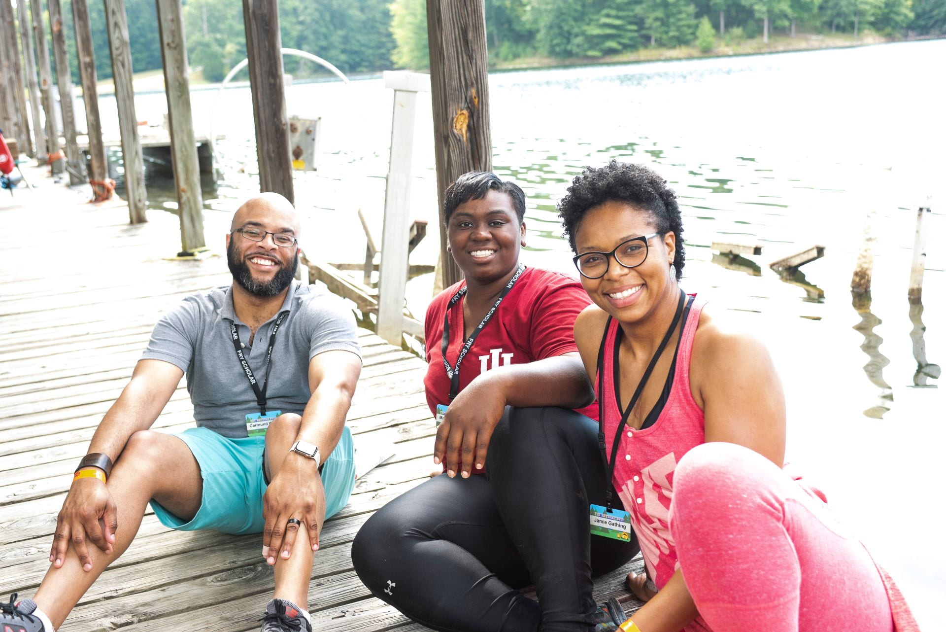 KODI advisors Carmund White, Maqubè Reese, and Jamie Gathing sit on a dock with water in the background.
