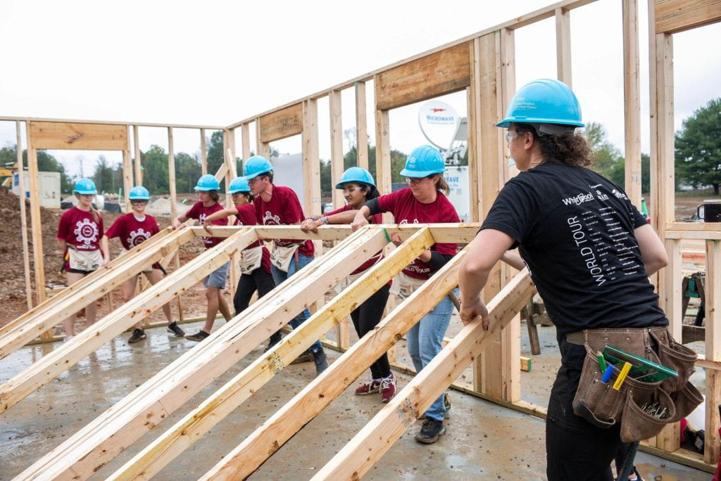 Student volunteers work together on framing a house.